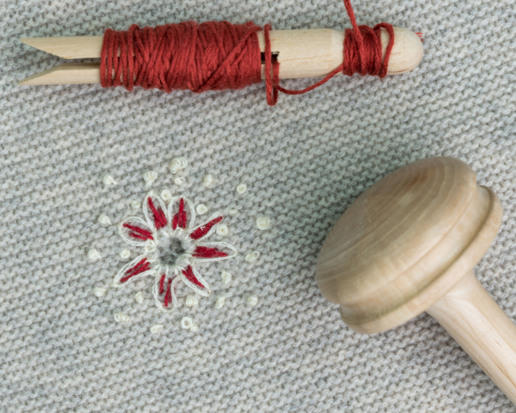 Spools of thread and a pin cushion laid out ready to use for wool darning