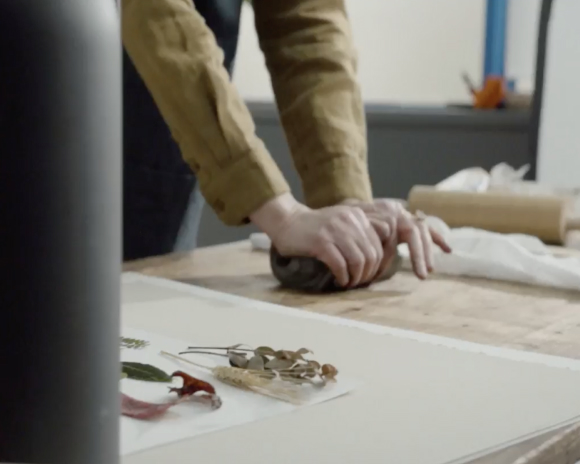 Hands rolling a wedge of clay