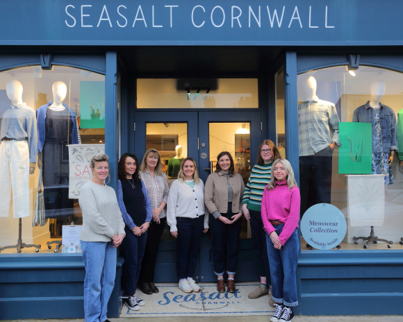 A group of smiling women stood in front of navy blue doors