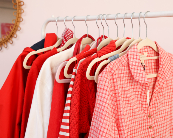 Clothes rail with different red clothes in front of a pale pink wall