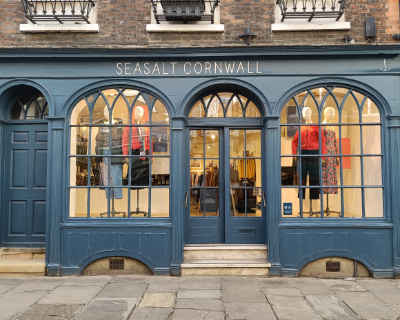 A navy blue shop front with 2 arched windows and a door in the middle