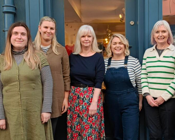 A group of women stood side by side smiling at the camera 