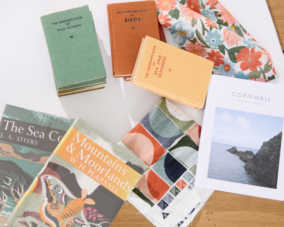 Pastel toned books scattered on a table with offcuts of printed fabric