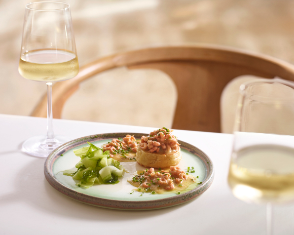 Potted Shrimp on crumpets with wine glass in the foreground